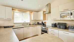 Eine moderne Küche mit weißen Schränken, einer Edelstahl-Mikrowelle, einer Kaffeemaschine und einem Toaster.