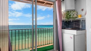 A balcony with a view of the ocean, a small table, and a refrigerator. - Studio "Porte Rouge 6" with Sea View (Le Pradet)