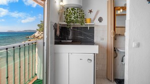 A compact kitchen with a view of the sea, a small sink, and a cabinet. - Studio "Porte Rouge 6" with Sea View (Le Pradet)