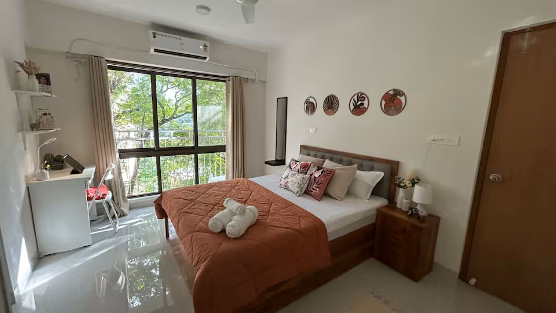 A bedroom with a bed, bedside table, chair, desk, and window.