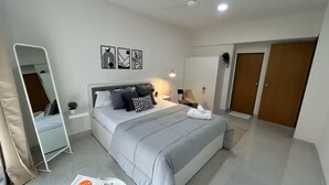 A modern bedroom with a bed, bedside tables, a mirror, and a wardrobe. - URBAN PAUSE, 2BHK Apt near BKC,airport&NMACC (Mumbai)