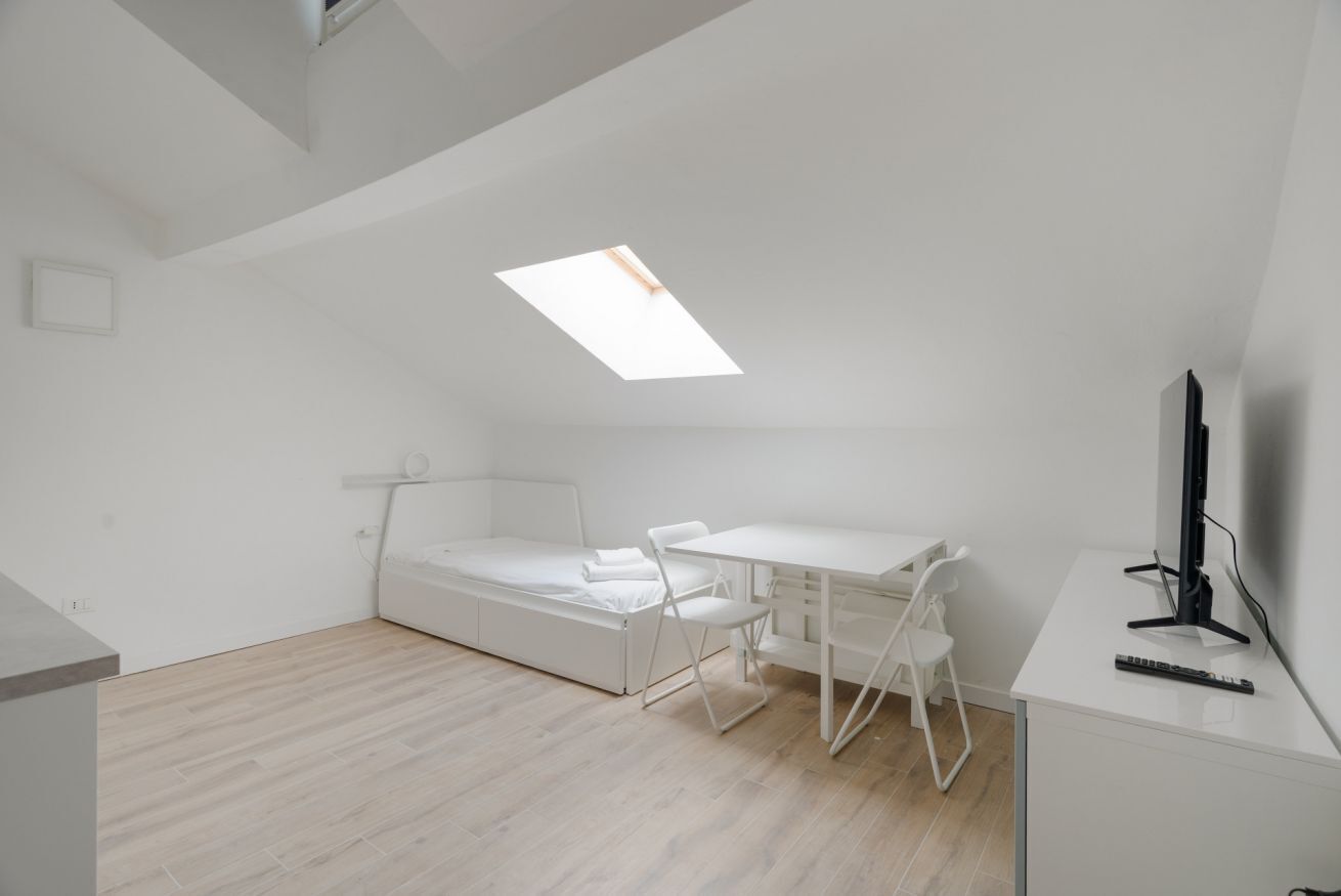 Ein gemütlicher Raum mit Bett, Schreibtisch, Stuhl und Fernseher.