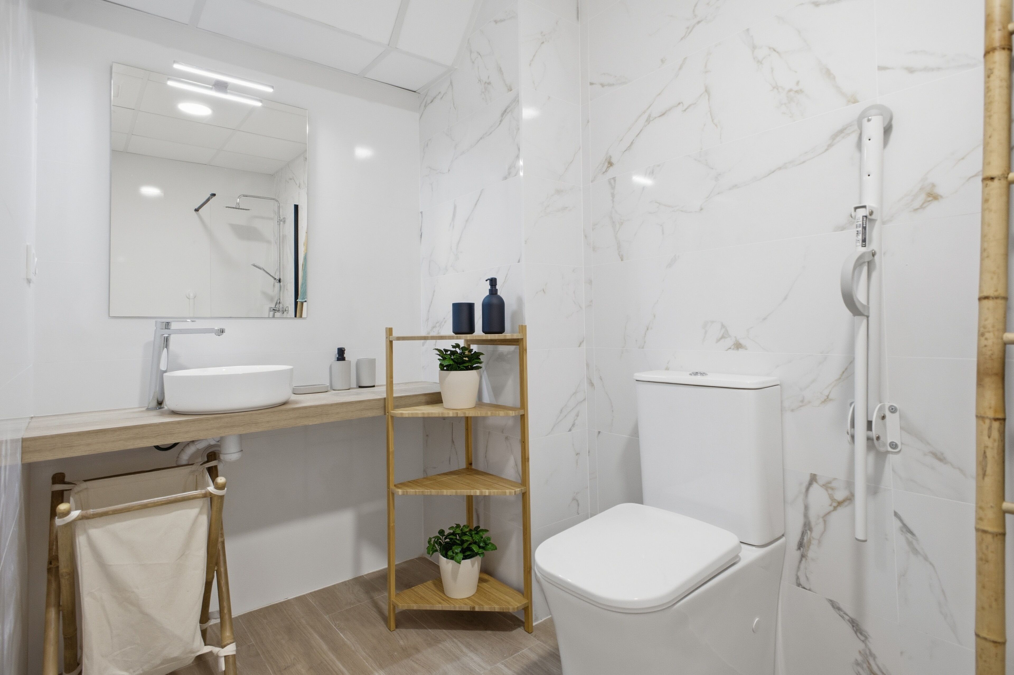 A modern bathroom with a white sink, mirror, toilet, and shower.