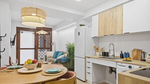 A modern kitchen with white cabinets, a wooden countertop, and a dining area with a table set for two. - Modern loft : Adapted : Smart TV : Air conditioning : 3 people : Air conditioner (València)