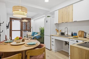 A modern kitchen with white cabinets, a wooden countertop, and a dining area with a table set for two. - Modern loft : Adapted : Smart TV : Air conditioning : 3 people : Air conditioner (València)