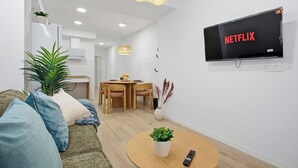 A modern living room with a flat-screen TV, a dining area, and a cozy seating area with a sofa and a coffee table. - Modern loft : Adapted : Smart TV : Air conditioning : 3 people : Air conditioner (València)