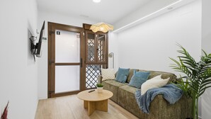 A modern living room with a wooden floor, a round coffee table, a sofa with cushions, a potted plant, and a door with a wooden frame. - Modern loft : Adapted : Smart TV : Air conditioning : 3 people : Air conditioner (València)