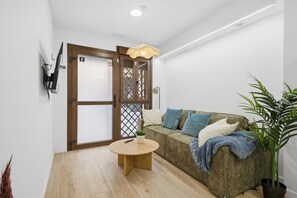 A modern living room with a wooden floor, a round coffee table, a sofa with cushions, a potted plant, and a door with a wooden frame. - Modern loft : Adapted : Smart TV : Air conditioning : 3 people : Air conditioner (València)
