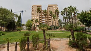 A multi-story residential building with a construction crane in the background, surrounded by palm trees and greenery. - Spacious 2-bedroom Apartment With Pool View in Oropesa del Mar (Oropesa del Mar)