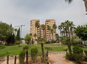 A multi-story residential building with a construction crane in the background, surrounded by palm trees and greenery. - Spacious 2-bedroom Apartment With Pool View in Oropesa del Mar (Oropesa del Mar)