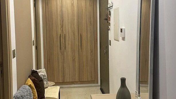 A hallway with a wooden wardrobe, a mirror, a vase, and a small table. - Cozy house in nouvelle soukra (Ariana)