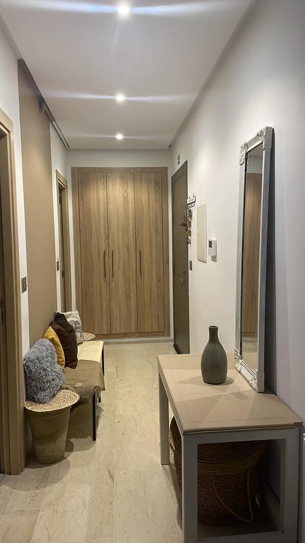 Ein Flur mit einem Holzschrank, einem Spiegel, einer Vase und einem kleinen Tisch.