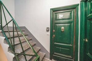 A staircase with green metal railings leading to a green door with a brass knocker. - The Yellow Nest Apartment in Trastevere (Roma)