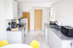 A compact kitchen with a washing machine, a microwave, and a toaster. - Comfortable base, central location with free parking (Stratford-upon-Avon)