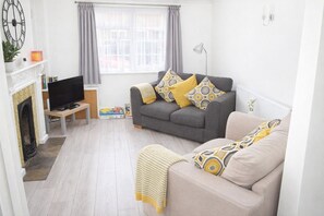 A living room with a sofa, a television, a fireplace, and a window with curtains. - Comfortable base, central location with free parking (Stratford-upon-Avon)