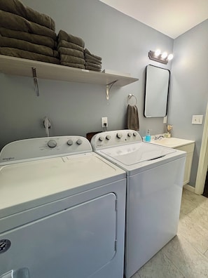 A laundry area with a stacked shelf of towels, a sink with a mirror, and two front-loading washers. - The Swish & Stay l Cozy 2BR I 15m to RRG I Wi-Fi (Stanton)
