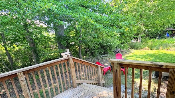 Une terrasse en bois avec une rambarde, entourée de verdure.