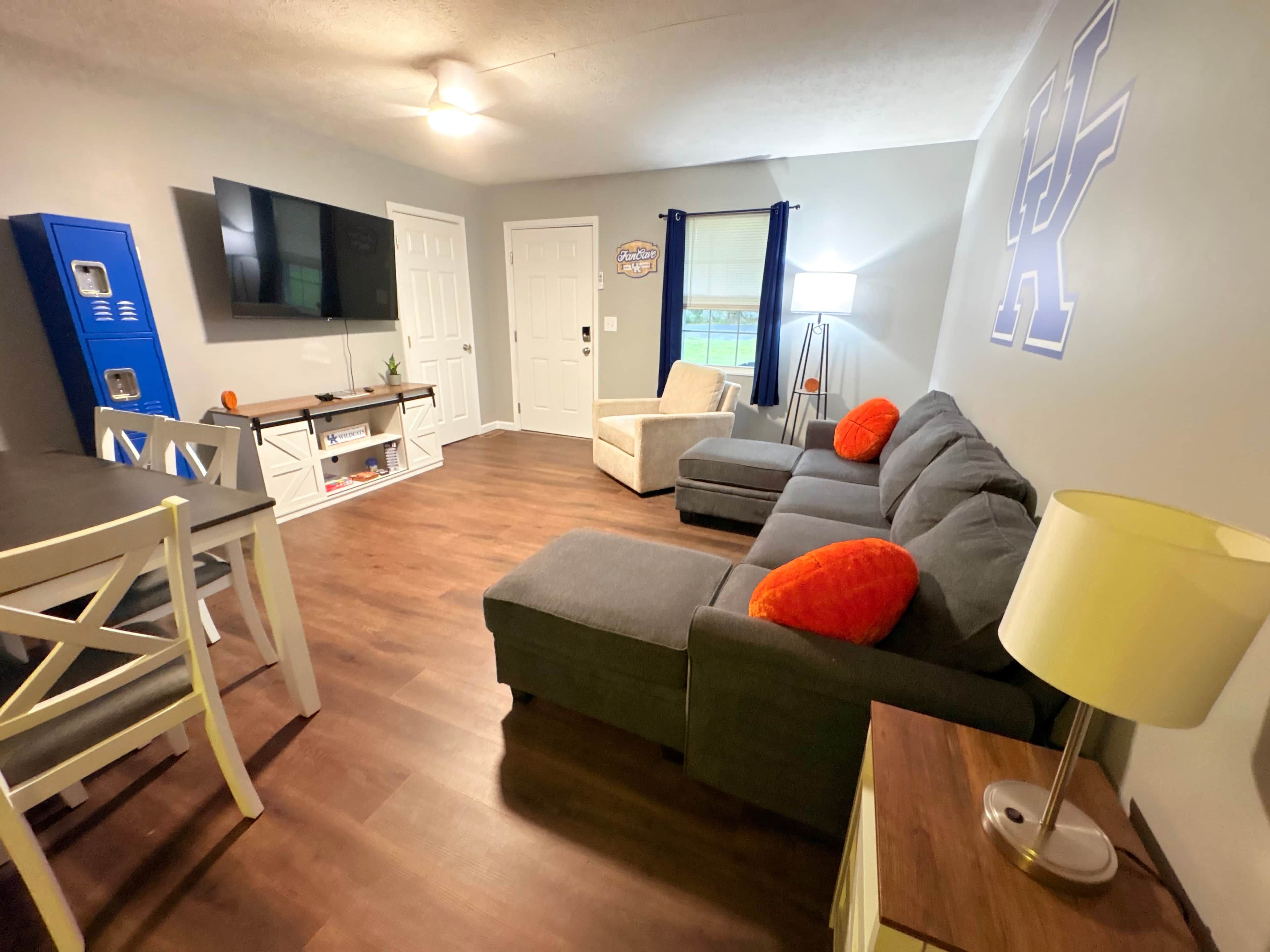 Een woonkamer met een bank, een eettafel, stoelen, een televisie en een lamp.