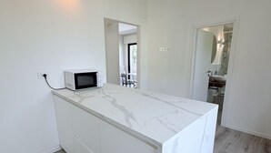 Una cucina moderna con un piano di lavoro in marmo, un forno a microonde e vista su un balcone.