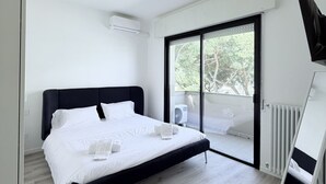 Una camera da letto moderna con un letto grande, una porta scorrevole in vetro su un balcone e un termosifone bianco.