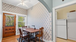 Una sala da pranzo con tavolo in legno, sedie, parete decorata e ventilatore a soffitto.