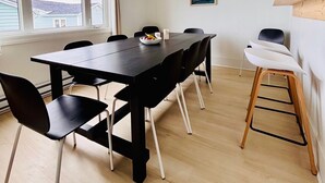 Et moderne spiseområde med et langt bord, sorte stole og en hvid bænk.