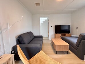 A modern living room with a sofa, a wooden coffee table, and a television.