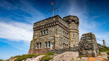 A stone building with a flag, windows, and a tower.