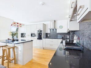 A modern kitchen with white cabinets, a black countertop, and a wooden stool.