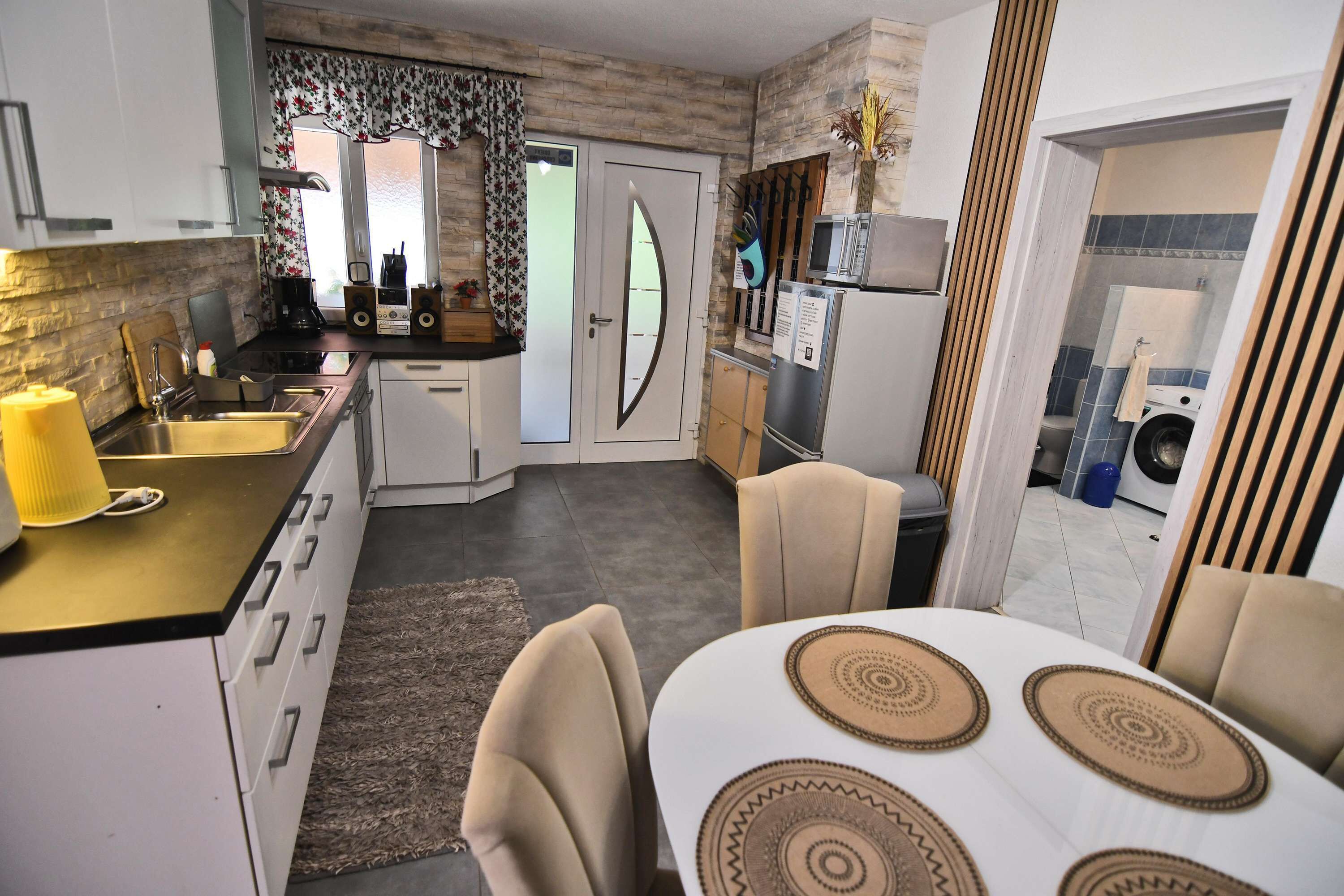 A compact kitchen with a dining area, featuring a built-in oven, microwave, and a small refrigerator.