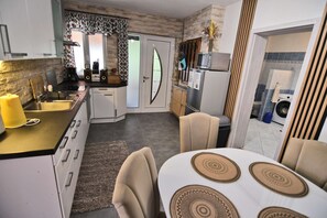 A compact kitchen with a dining area, featuring a built-in oven, microwave, and a small refrigerator.