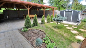 A covered patio area with a wooden bench and a small garden with various plants. - Apartment V+K – Cozy 2BR near High Tatras, Štrba (Štrba)
