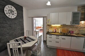 Eine moderne Küche mit weißen Schränken, einer Wand als Steinakzent und einem Essbereich mit einem gestreiften Tisch und Stühlen.