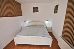Habitació estreta amb un llit individual, dues taules de nit i dues làmpades fixades a la paret.