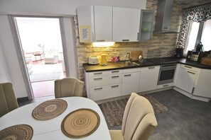 Une cuisine moderne avec des meubles blancs, un pare-feu en pierre et un coin repas comprenant une table et des chaises.