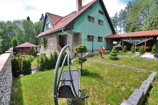 A two-story house with a green facade and a red-tiled roof.