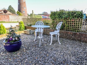 Eine Terrasse mit Tisch und Stühlen, einem Blumentopf und einer Ziegelwand.