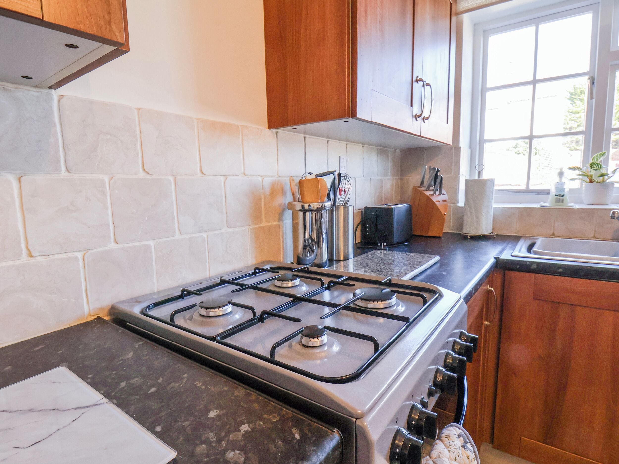 A kitchen with a gas stove, wooden cabinets, a window, and a countertop.