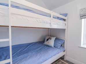 Ein Stockbett mit einer blauen Decke und einem Kissen mit einem Pinguin-Motiv.