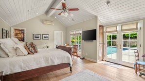 Une chambre avec un lit, un ventilateur de plafond et une vue sur une piscine.