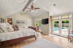 Une chambre avec un lit, un ventilateur de plafond et une vue sur une piscine.