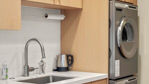 Une cuisine équipée d’un évier en acier inoxydable, d’une bouilloire et d’un lave-linge encastré.