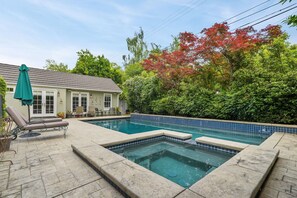 Une piscine bordée de carreaux, avec des chaises longues et un patio couvert.