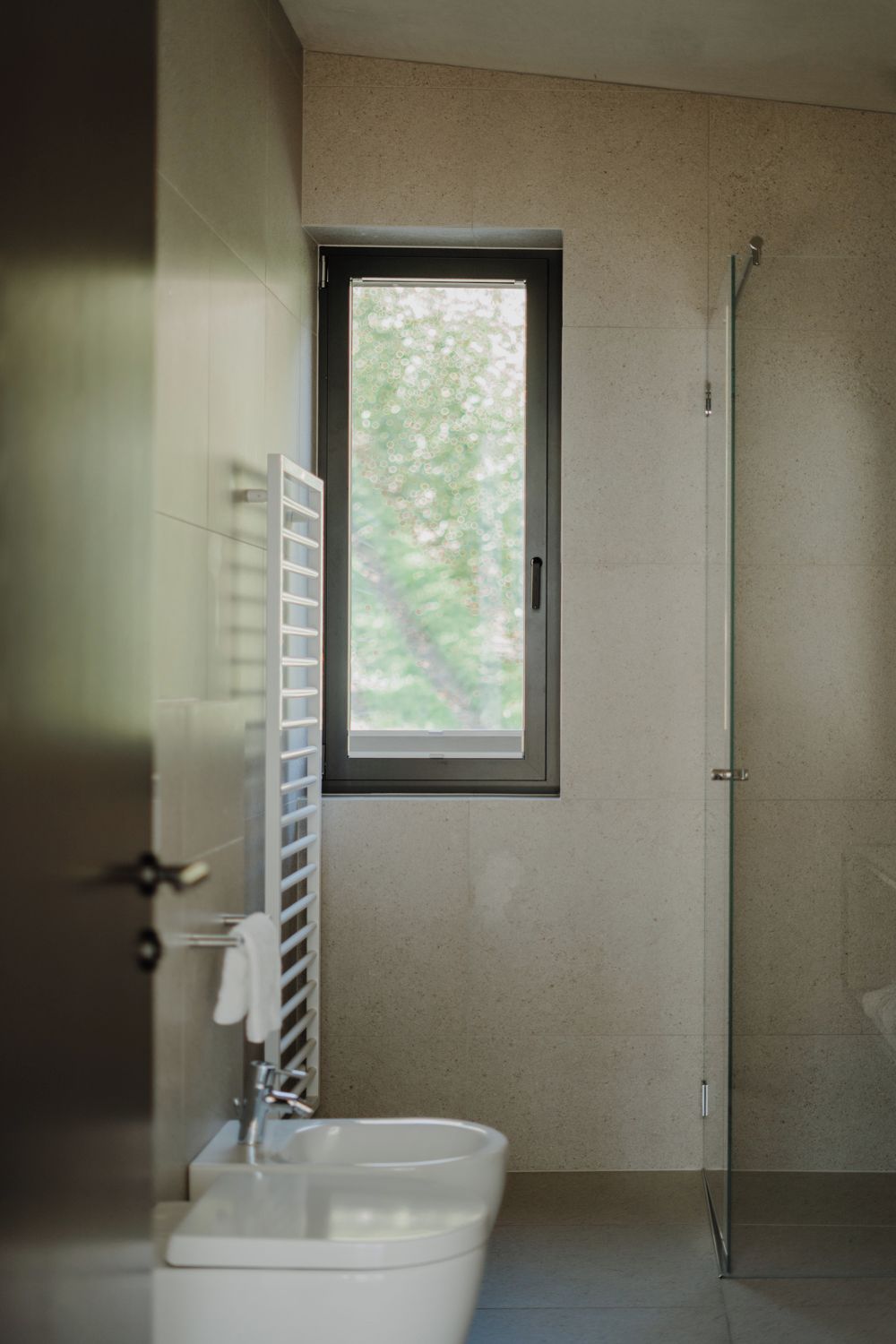 A modern bathroom with a shower, a window, and a towel rack.