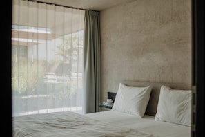 Une chambre d’hôtel avec un lit, une table de chevet, une tasse et une vue sur l’extérieur.
