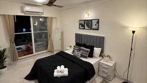 Et moderne soveværelse med en seng, sengeborde, en gulvlampe og en ventilator i loftet.