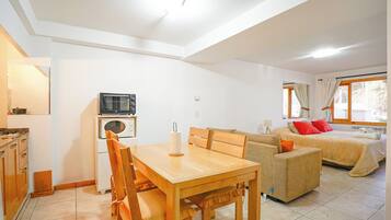 Un espacio habitable compacto con kitchenette, comedor, sofá y cama.