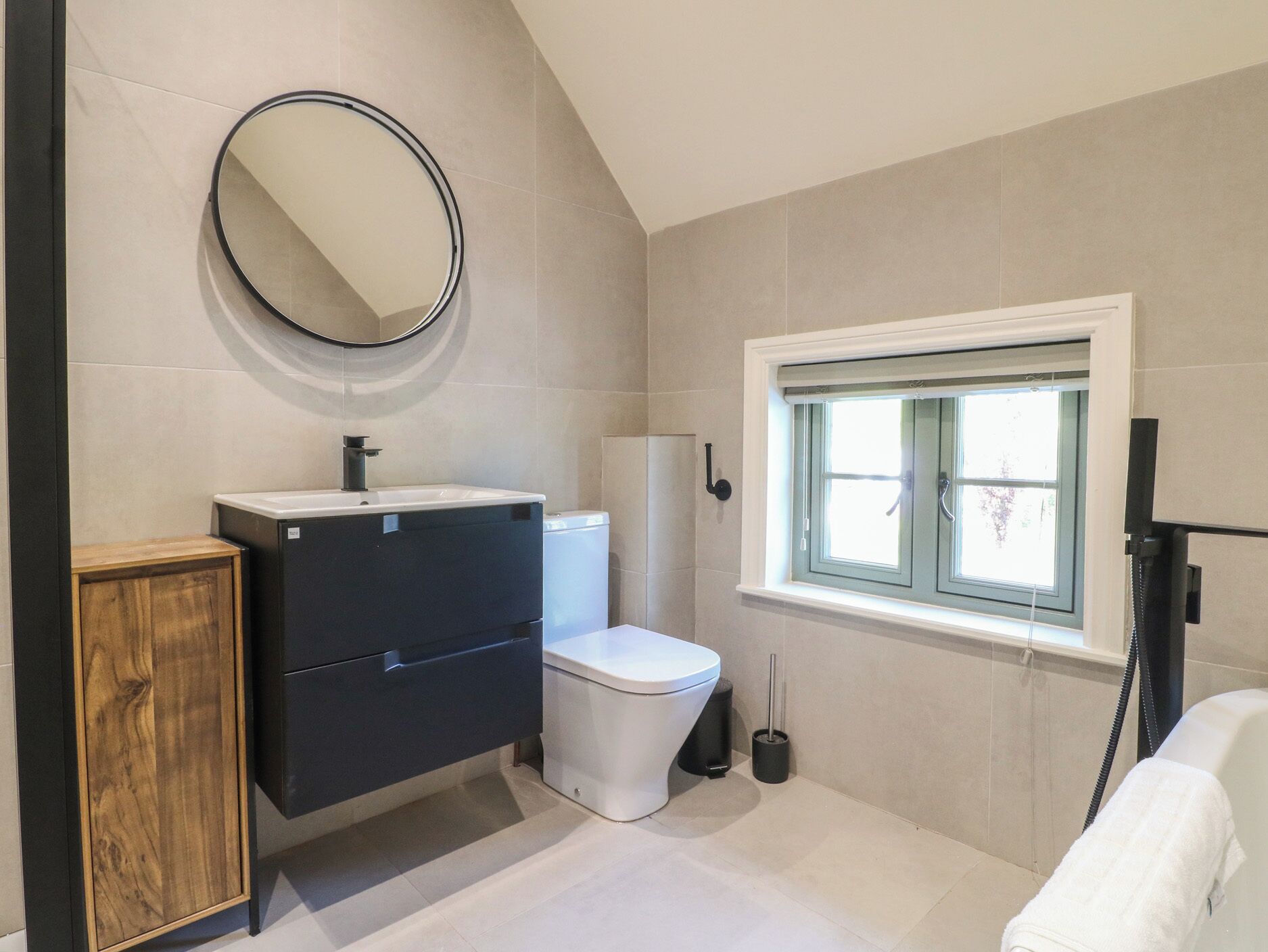 A bathroom with a toilet, sink, mirror, window, and a towel rack.