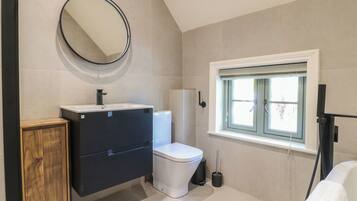 A bathroom with a toilet, sink, mirror, window, and a towel rack.