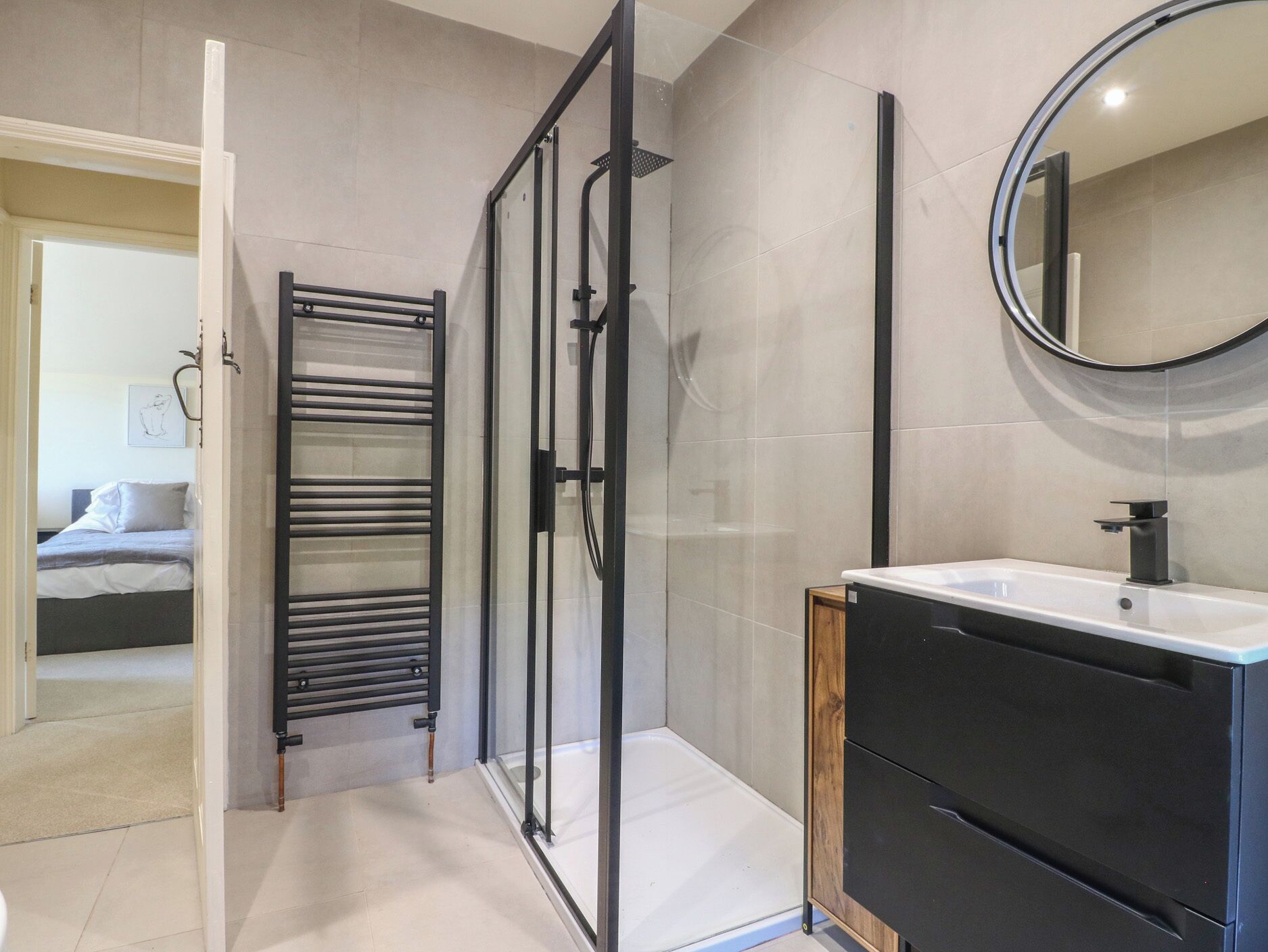 Une salle de bain moderne avec une douche à parois de verre, un meuble-lavabo noir et un grand miroir.